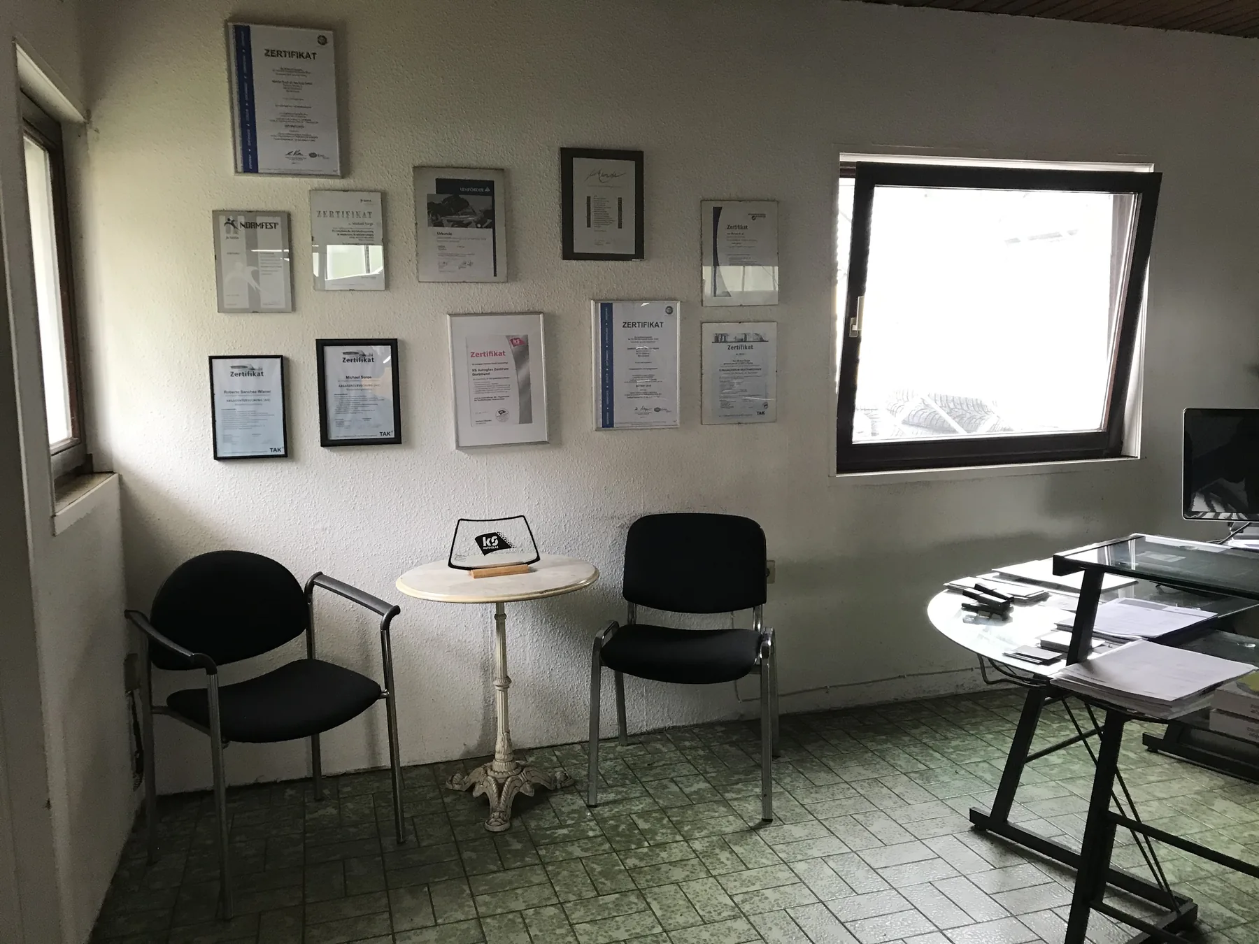 Empfangsraum der Rando Kfz Werkstatt mit Sitzgelegenheiten und Zertifikaten an der Wand